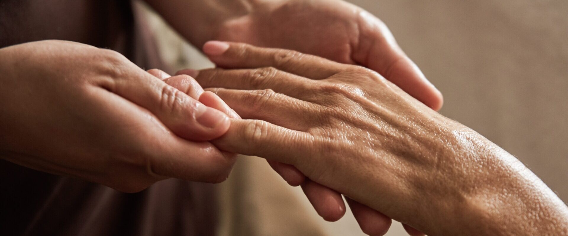 Nahaufnahme einer Person, die sanft die Hand einer anderen Person massiert und so Fürsorge und Entspannung ausdrückt.