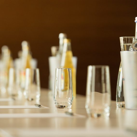 Tagungsblöcke, Gläser und Getränke auf Tischen in einer Detailaufnahme.