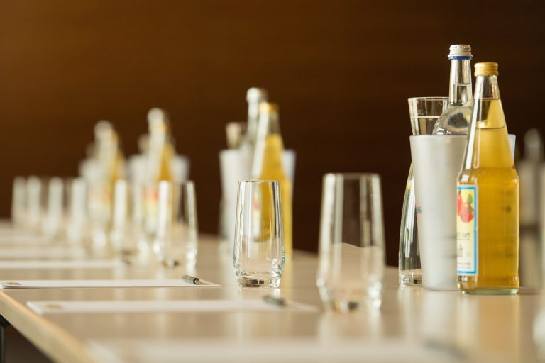 Tagungsblöcke, Gläser und Getränke auf Tischen in einer Detailaufnahme.