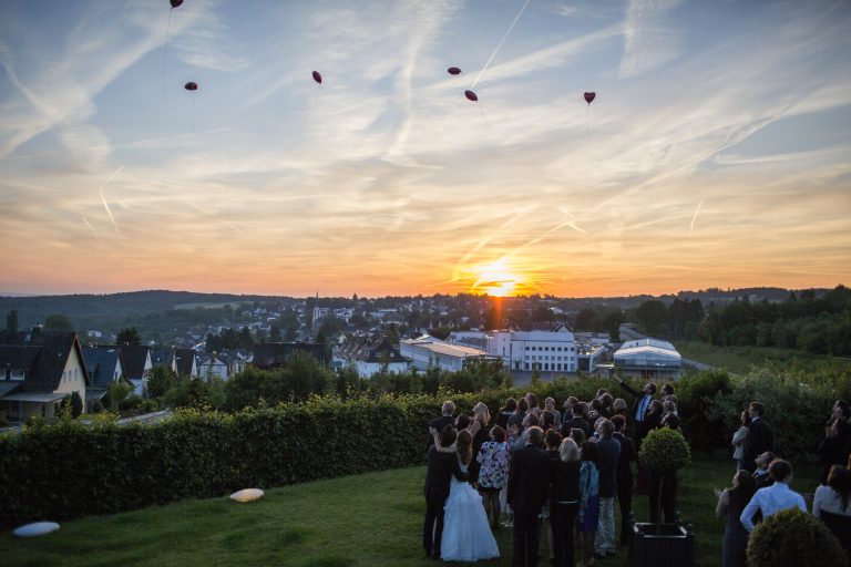 Hochzeitsgesellschaft lässt Luftballons in den Abendhimmel vor einem Sonnenuntergang steigen, mit Blick auf Höhr-Grenzhausen.