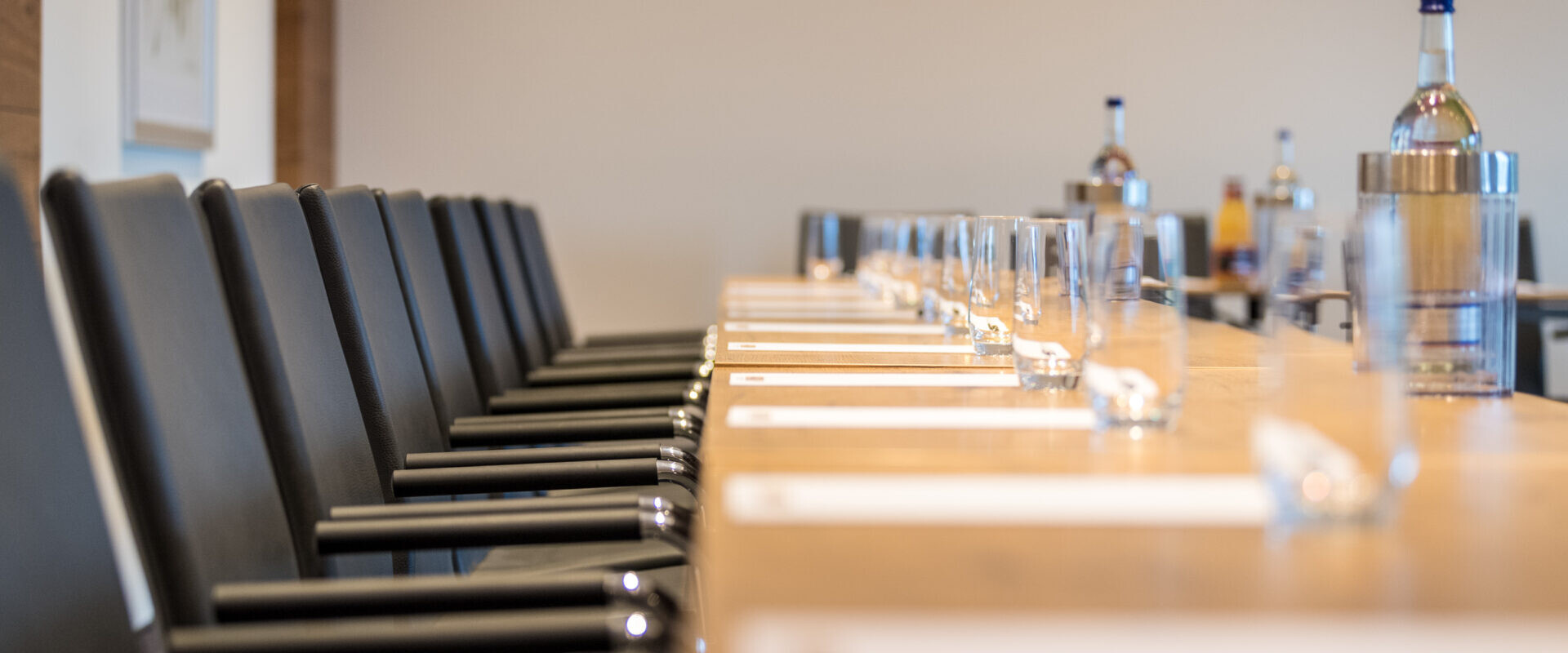 Blick über eine leere Stuhlreihe bzw. Tische mit Schreibblöcken, Gläsern und Getränken.