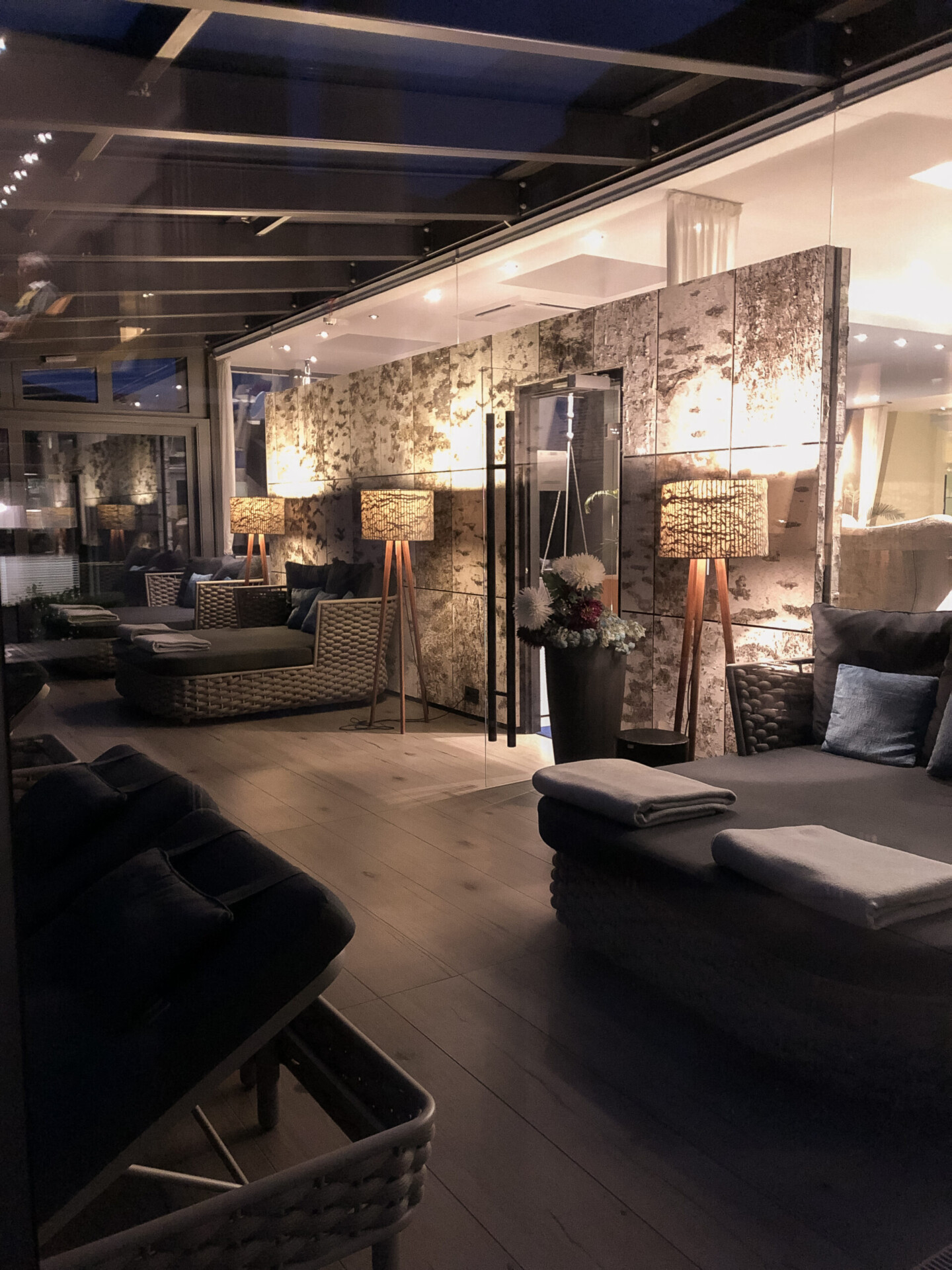 Eine gemütliche Lounge im Innenbereich mit Korbsofas, Stehlampen, sanfter Beleuchtung und einer modernen, entspannten Atmosphäre.