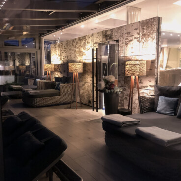 Eine gemütliche Lounge im Innenbereich mit Korbsofas, Stehlampen, sanfter Beleuchtung und einer modernen, entspannten Atmosphäre.