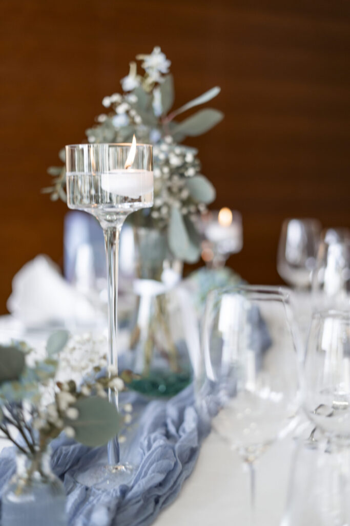 Detail einer blau-grünen Tischdekoration mit einer brennenden Kerze