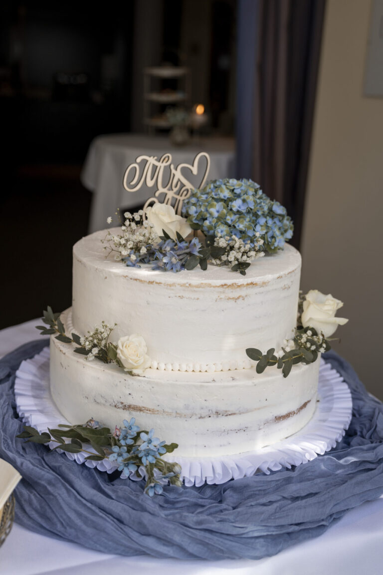 Eine weiße Hochzeitstorte mit blauen und weißen Blumen