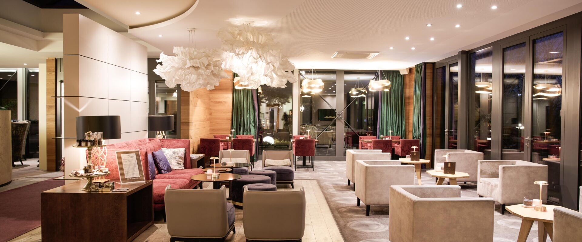 Moderne Hotellounge mit Plüschsitzen, stilvoller Beleuchtung und großen Fenstern, die eine gemütliche und elegante Atmosphäre schaffen.