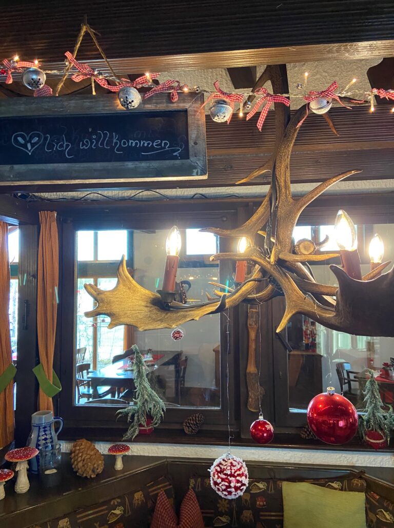 Adventsmarkt im Flürchen: Ein rustikaler, weihnachtlich geschmückter Raum mit Ornamenten, einer Kreidetafel mit der Aufschrift "Willkommen" und einem Lichterleuchter aus Geweih.